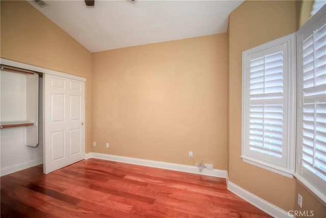 unfurnished bedroom with hardwood / wood-style flooring and lofted ceiling