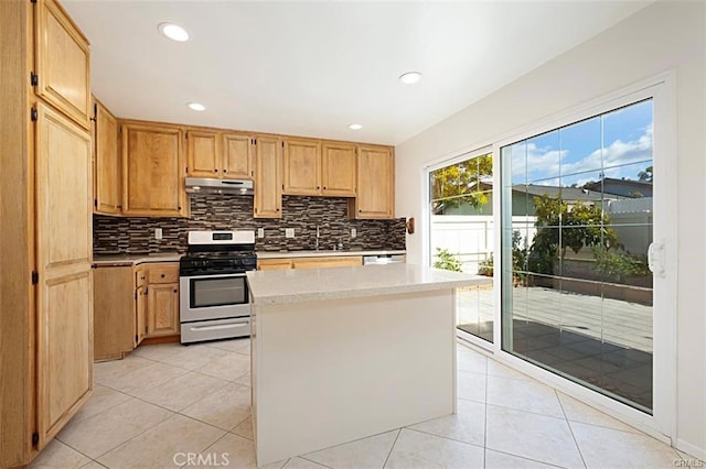 kitchen with sink, a center island, light tile patterned floors, and stainless steel gas range