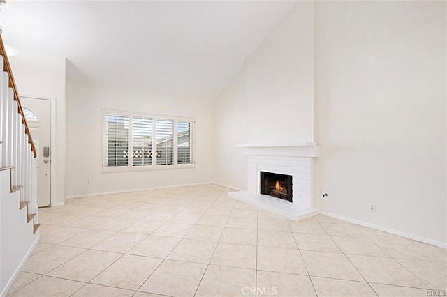 unfurnished living room with light tile patterned floors, vaulted ceiling, and a brick fireplace