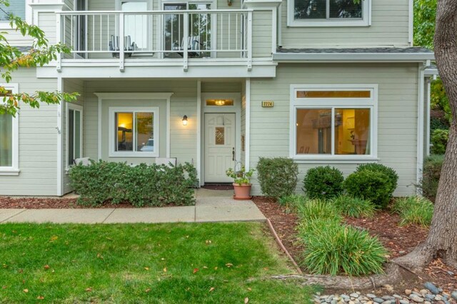 entrance to property featuring a balcony and a yard