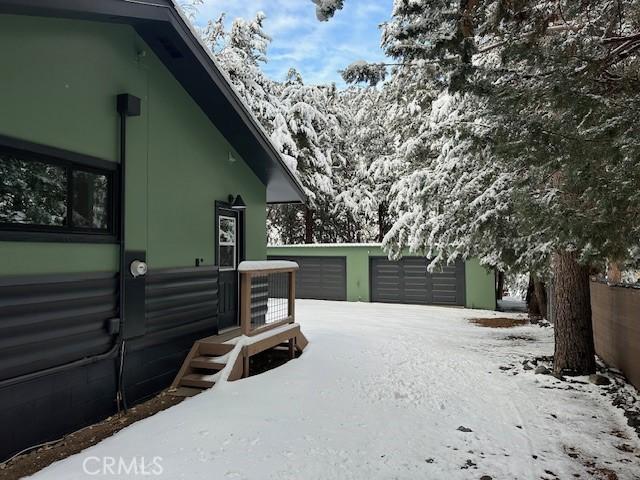 yard layered in snow featuring a garage and an outdoor structure