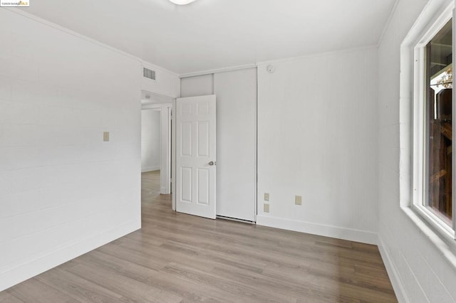 unfurnished room featuring a healthy amount of sunlight, ornamental molding, and light wood-type flooring