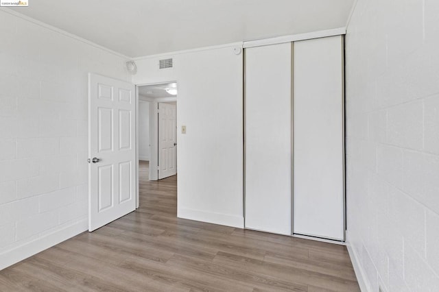 unfurnished bedroom with a closet, light hardwood / wood-style flooring, and crown molding