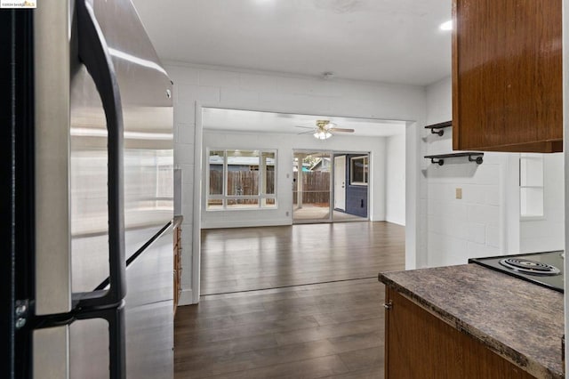 kitchen with black electric cooktop, stainless steel fridge, ceiling fan, and dark hardwood / wood-style floors