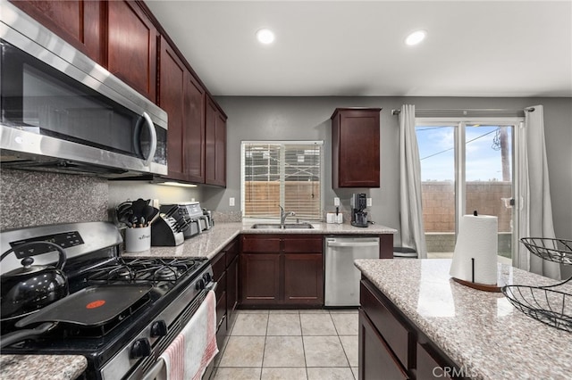 kitchen featuring light stone countertops, appliances with stainless steel finishes, light tile patterned floors, and sink