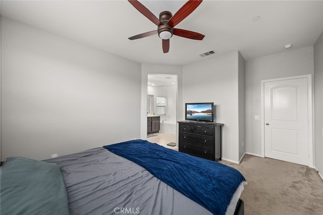 bedroom with ceiling fan, light colored carpet, and ensuite bathroom