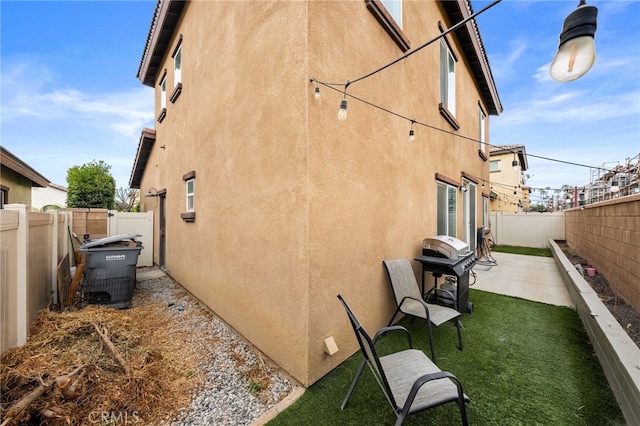 view of side of property featuring a lawn and a patio area