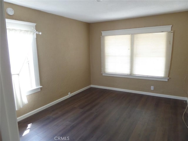 unfurnished room with dark hardwood / wood-style floors and a wealth of natural light