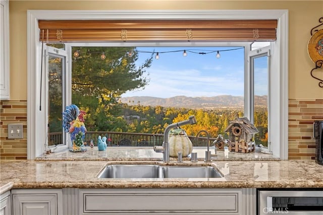 kitchen featuring a mountain view, sink, white cabinetry, and decorative backsplash