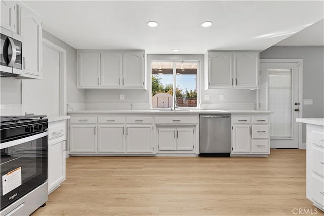 kitchen featuring white cabinets, light wood-type flooring, stainless steel appliances, and sink