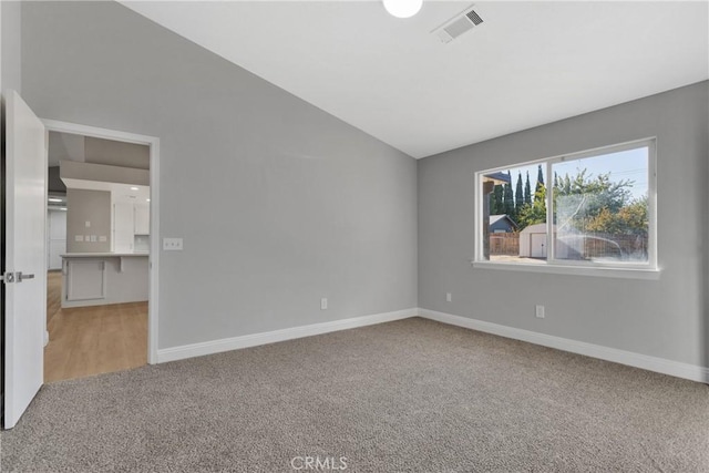 carpeted empty room featuring lofted ceiling