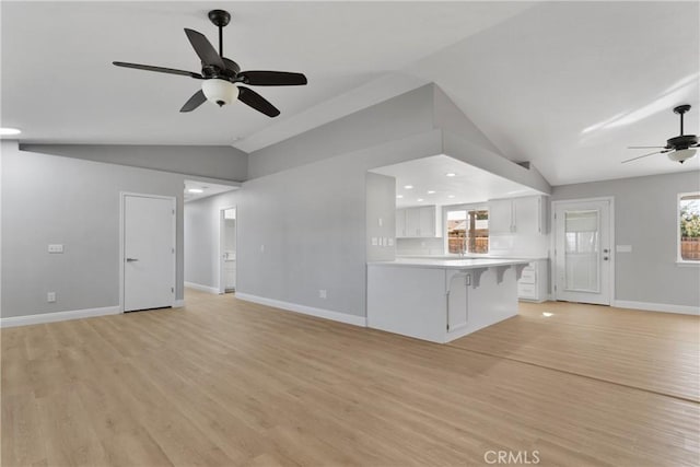 unfurnished living room featuring light hardwood / wood-style floors, vaulted ceiling, and ceiling fan