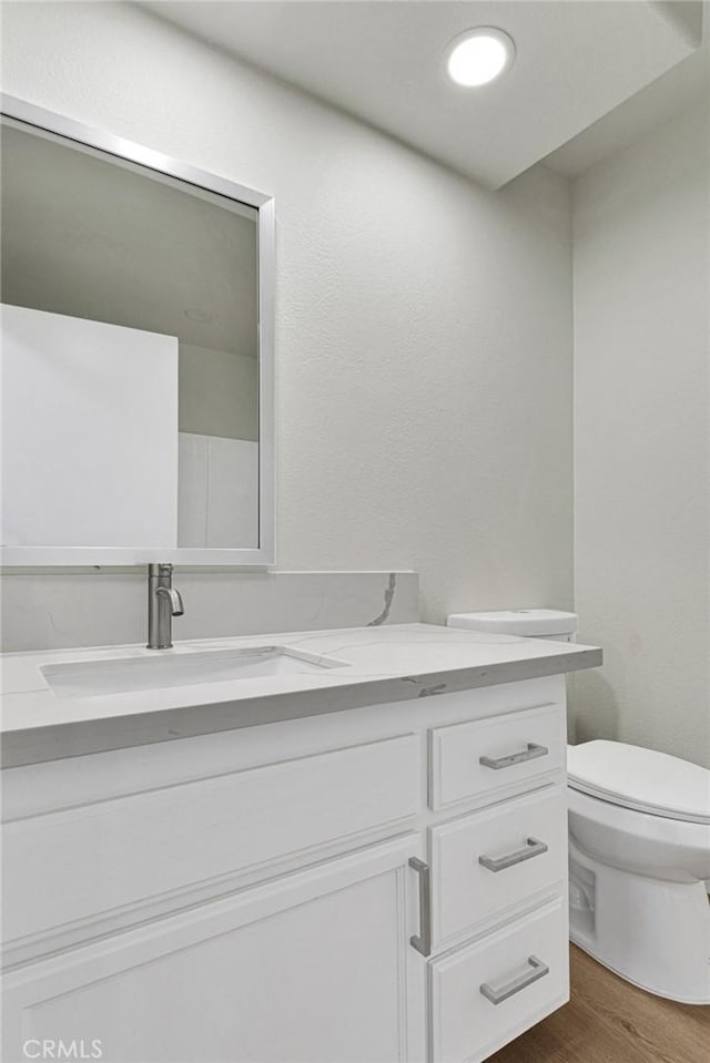 bathroom with toilet, vanity, and hardwood / wood-style flooring