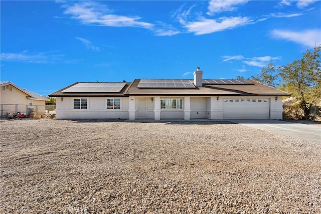 single story home featuring solar panels and a garage