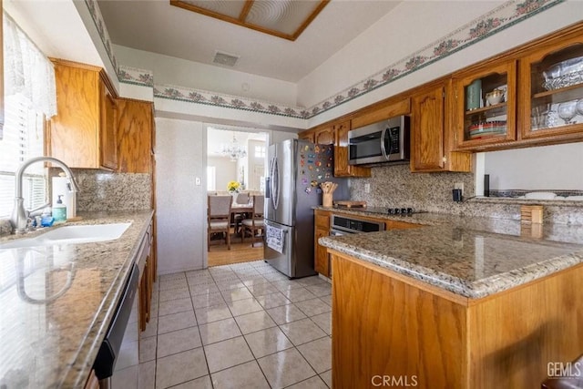 kitchen featuring appliances with stainless steel finishes, backsplash, light stone counters, sink, and light tile patterned floors