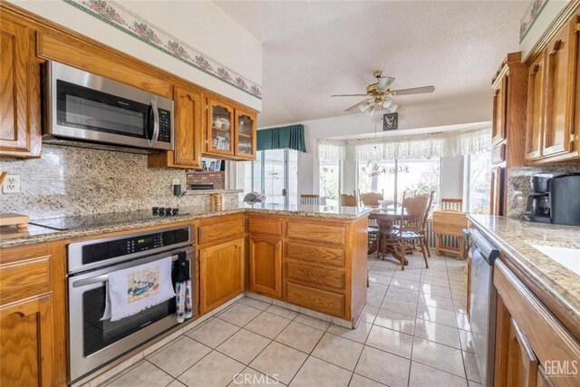 kitchen with ceiling fan, stainless steel appliances, kitchen peninsula, decorative backsplash, and light tile patterned floors