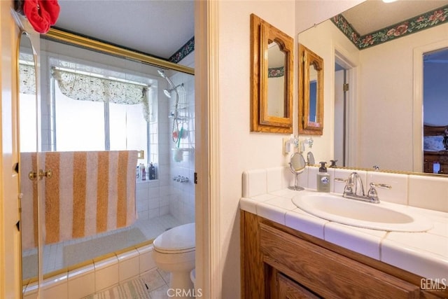 bathroom with tile patterned floors, vanity, toilet, and tiled shower