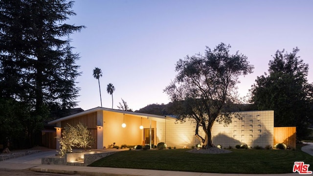 property exterior at dusk with a lawn