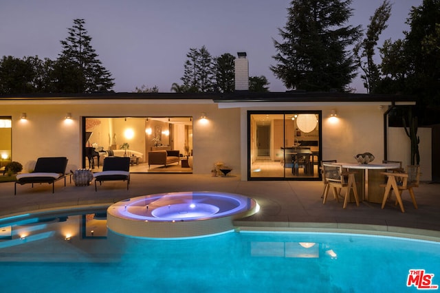 pool at dusk with an outdoor living space, a patio area, and an in ground hot tub