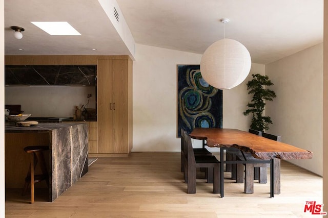 dining room featuring light hardwood / wood-style floors and vaulted ceiling