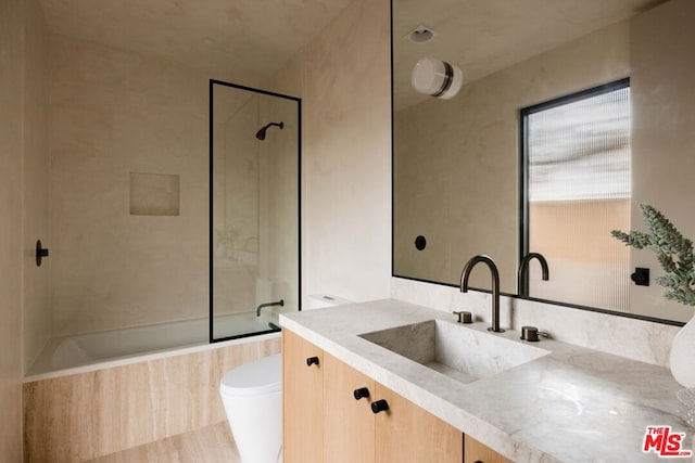 full bathroom featuring vanity, tiled shower / bath combo, and toilet