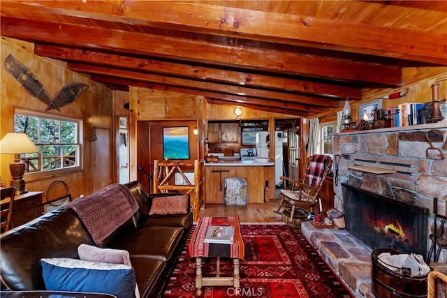 living room featuring wood-type flooring, wooden walls, vaulted ceiling with beams, a fireplace, and wood ceiling