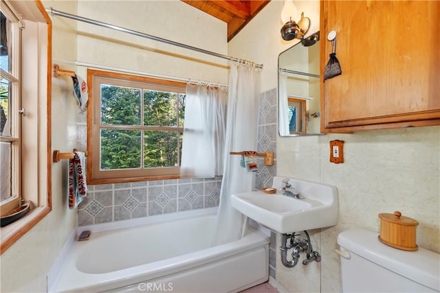 bathroom featuring beam ceiling, toilet, and shower / tub combo with curtain