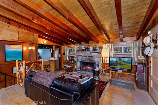 living room with a fireplace, lofted ceiling with beams, light hardwood / wood-style flooring, and wooden walls