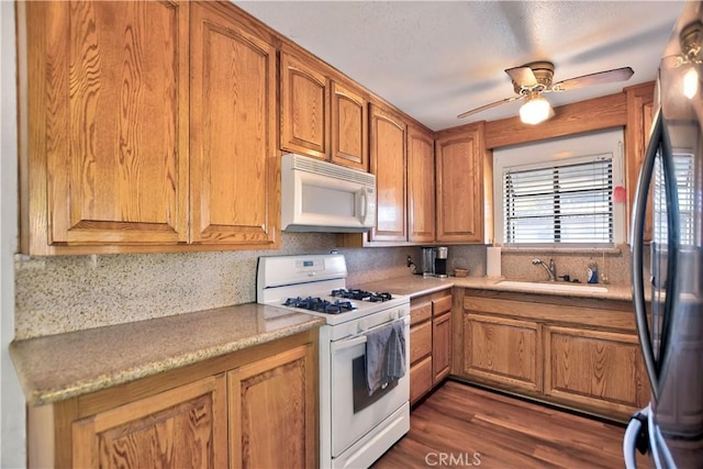 kitchen featuring ceiling fan, sink, dark hardwood / wood-style flooring, backsplash, and white appliances