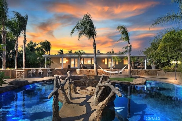 pool at dusk with a patio area