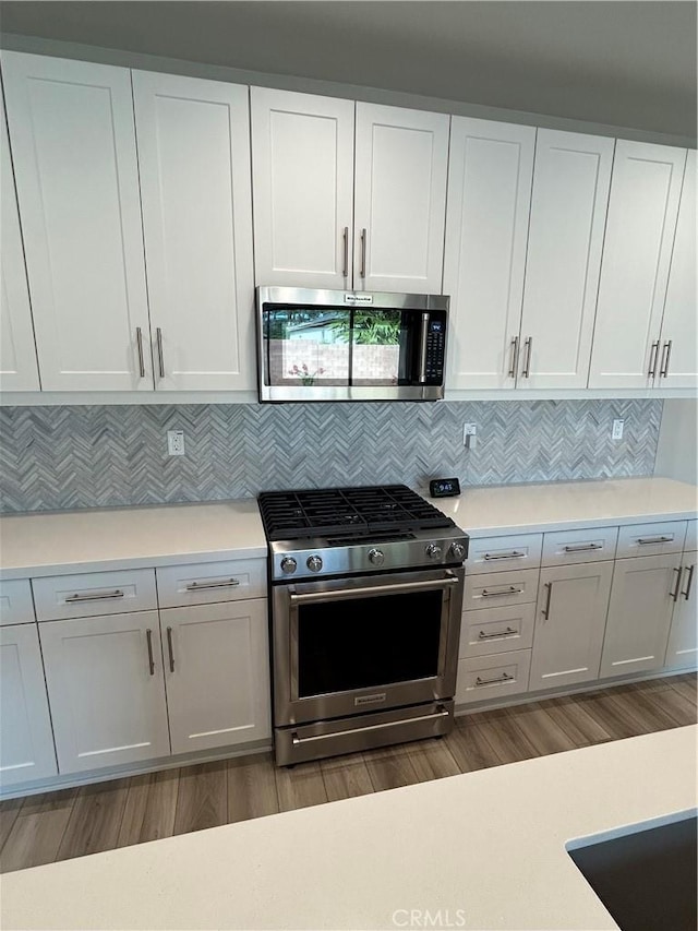 kitchen with stainless steel appliances, decorative backsplash, and white cabinets