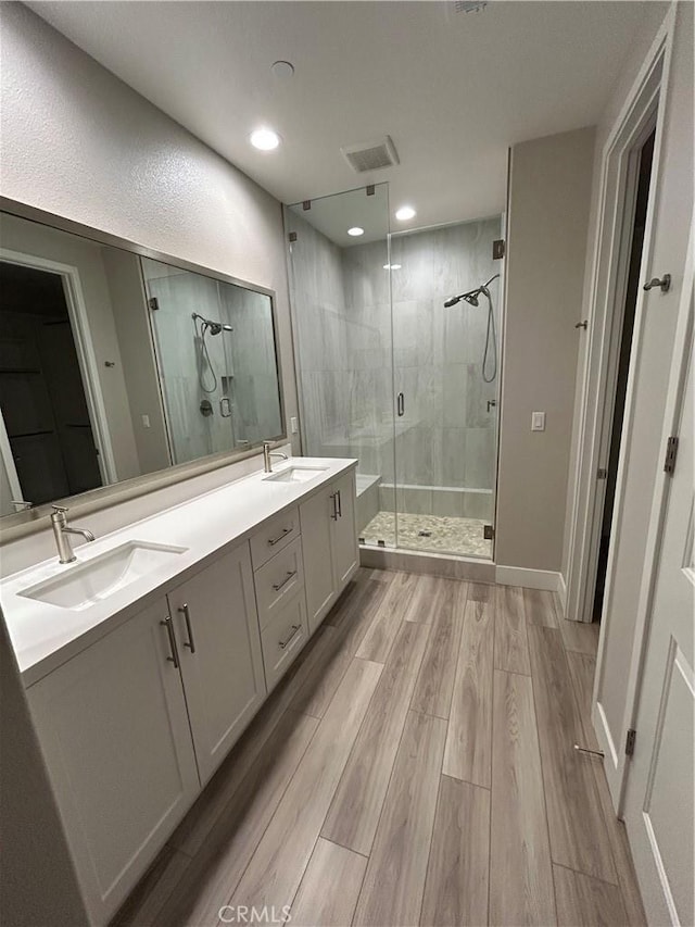 bathroom featuring hardwood / wood-style flooring, a shower with shower door, and vanity