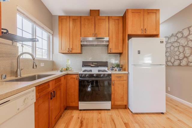 kitchen with backsplash, light wood-type flooring, white appliances, and sink