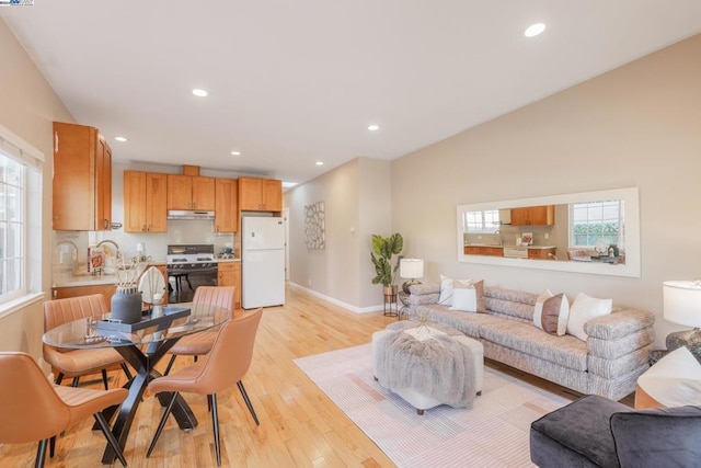 living room with light hardwood / wood-style flooring, vaulted ceiling, and sink