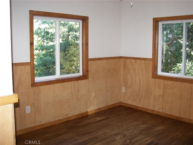 unfurnished room featuring dark hardwood / wood-style floors and wood walls