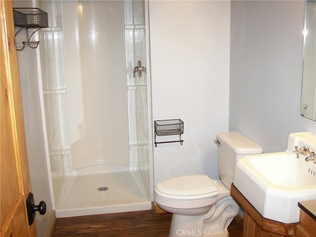 bathroom featuring a shower, vanity, hardwood / wood-style flooring, and toilet