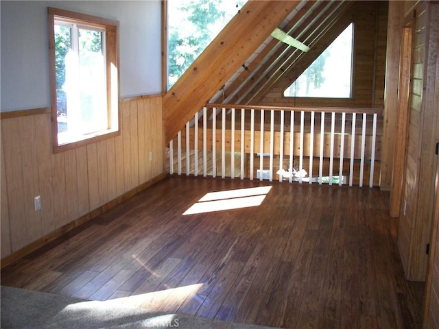 bonus room featuring wood walls, lofted ceiling, and dark wood-type flooring