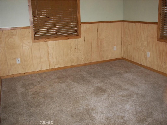 carpeted spare room with wooden walls