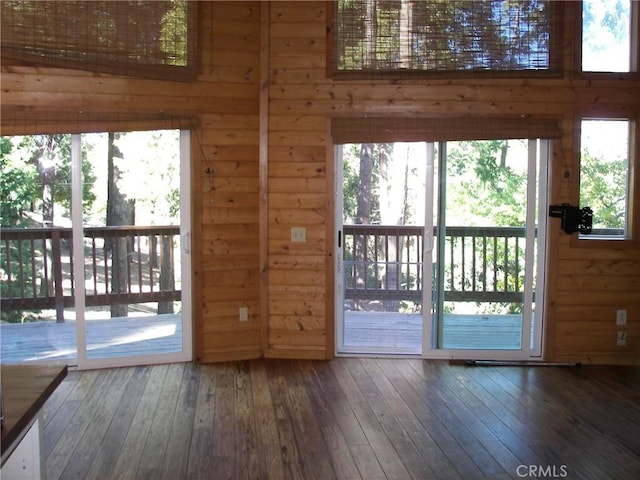 entryway with dark hardwood / wood-style floors, a healthy amount of sunlight, and wooden walls