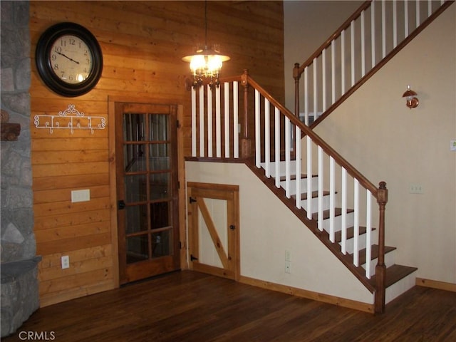 staircase featuring hardwood / wood-style flooring, wood walls, and a chandelier