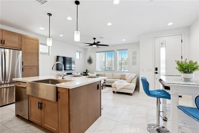 kitchen featuring sink, hanging light fixtures, ceiling fan, an island with sink, and stainless steel appliances