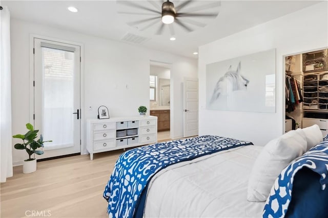 bedroom with ceiling fan, light hardwood / wood-style flooring, a spacious closet, connected bathroom, and a closet