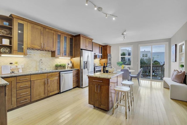 kitchen featuring light stone counters, light wood-type flooring, stainless steel appliances, and a kitchen island