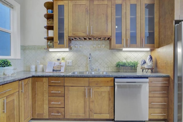 kitchen featuring appliances with stainless steel finishes, dark stone countertops, backsplash, and sink