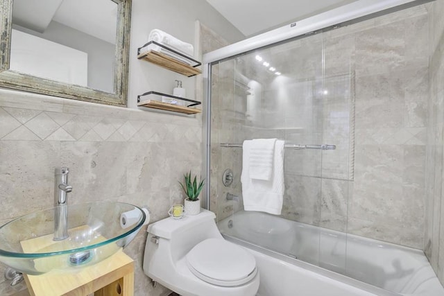 full bathroom with toilet, bath / shower combo with glass door, tile walls, and vanity