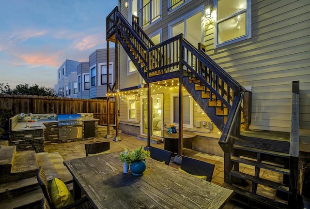 patio terrace at dusk featuring an outdoor kitchen and grilling area