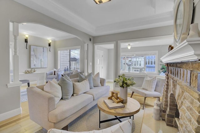 living room with a fireplace, crown molding, and light wood-type flooring