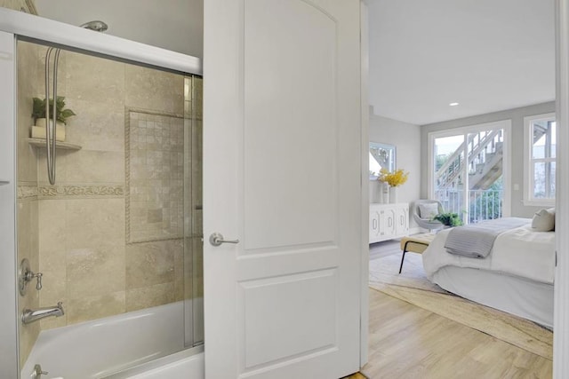 bathroom featuring hardwood / wood-style floors and shower / bath combination with glass door