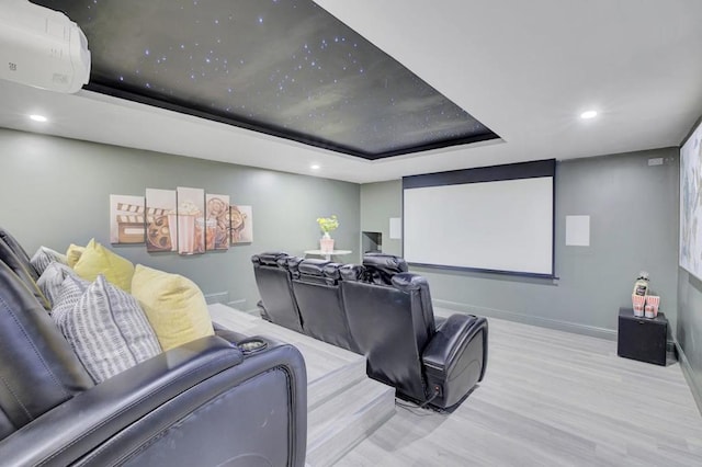 home theater room with a raised ceiling and light wood-type flooring