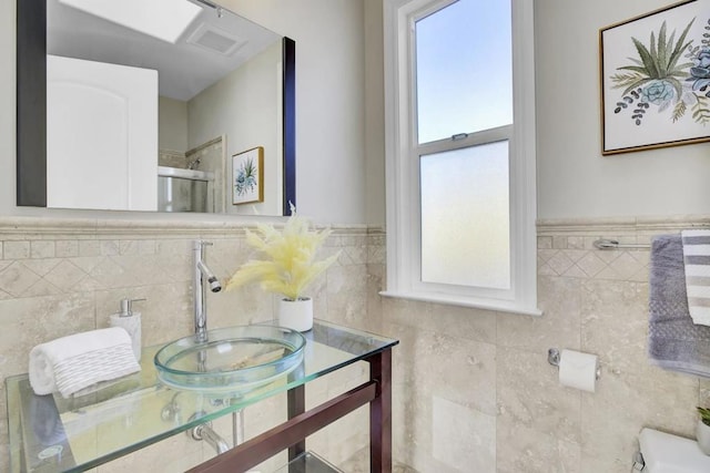 bathroom featuring a shower with door, tile walls, and vanity